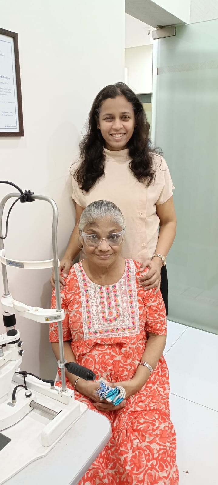 Doctor standing with a patient beside slit lamp equipment